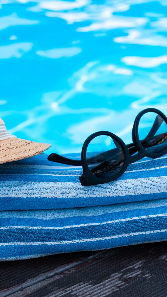 a hat, sunglasses and towel are placed on a pool deck at The Soltera Rolling Pines