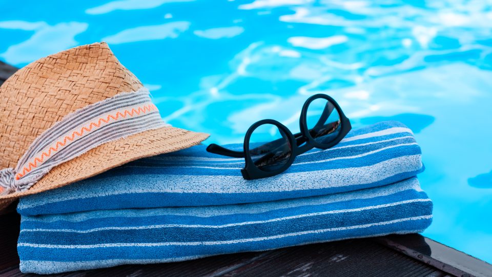 a hat, sunglasses and towel are placed on a pool deck at The Soltera Rolling Pines