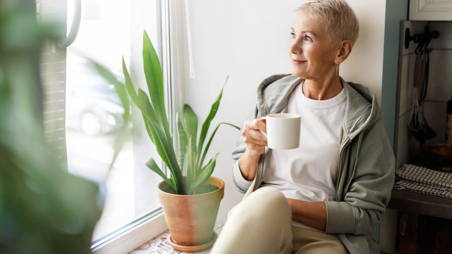 a woman sitting on a window sill with a cup of coffee at The Soltera Rolling Pines