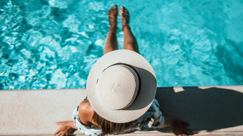 a woman in a hat is sitting by a pool